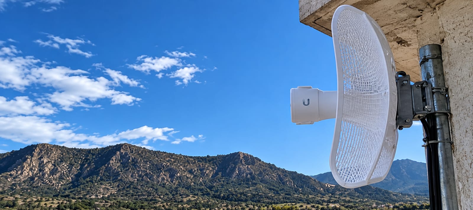 Una antena de internet inalámbrico frente a un paisaje de montañas.